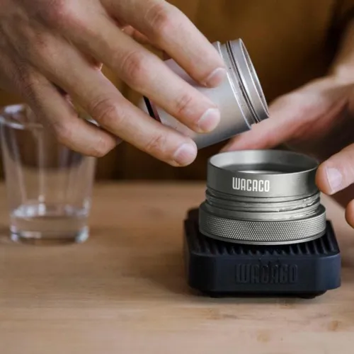 Filling the Picopresso with coffee grinds from the base of a hand operated coffee grinder